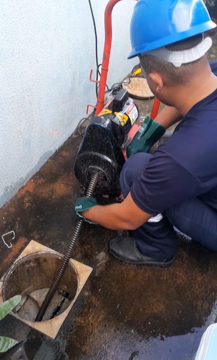 Profissional especializado trabalhando com máquina de desentupimento